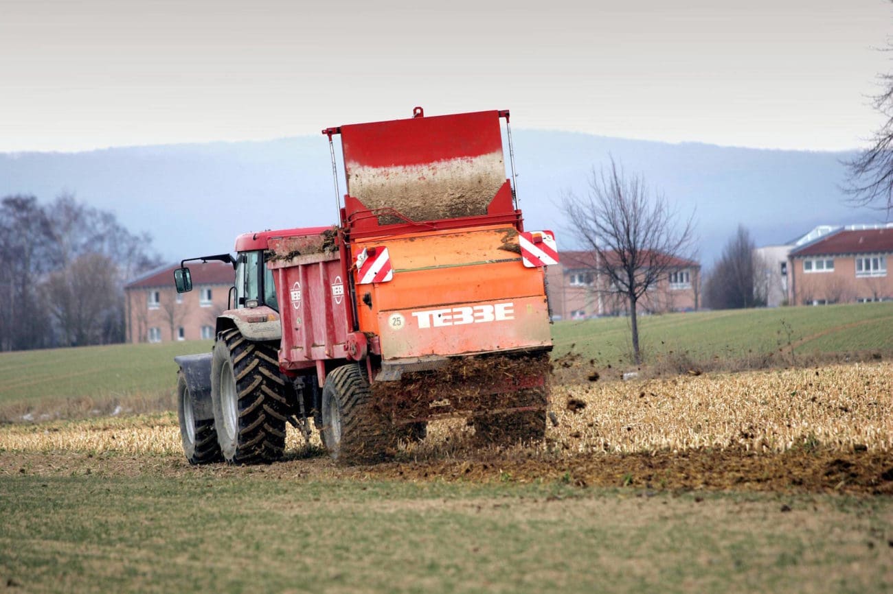 Traktor streut Mist auf einem Feld in Elze - Niedersachsen