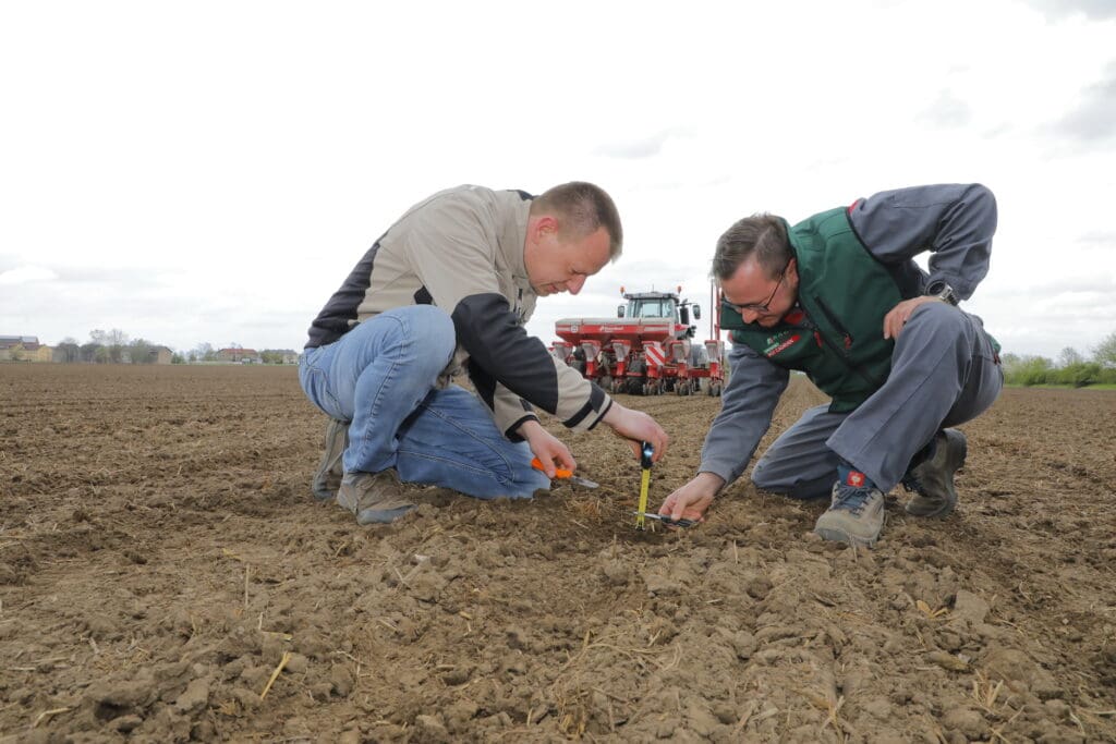 Pflanzenbauleiter Maurice Ullmann (l.) und  Mitarbeiter Sebastian Sparing (r.) kontrollieren die Ablagetiefe der Saat