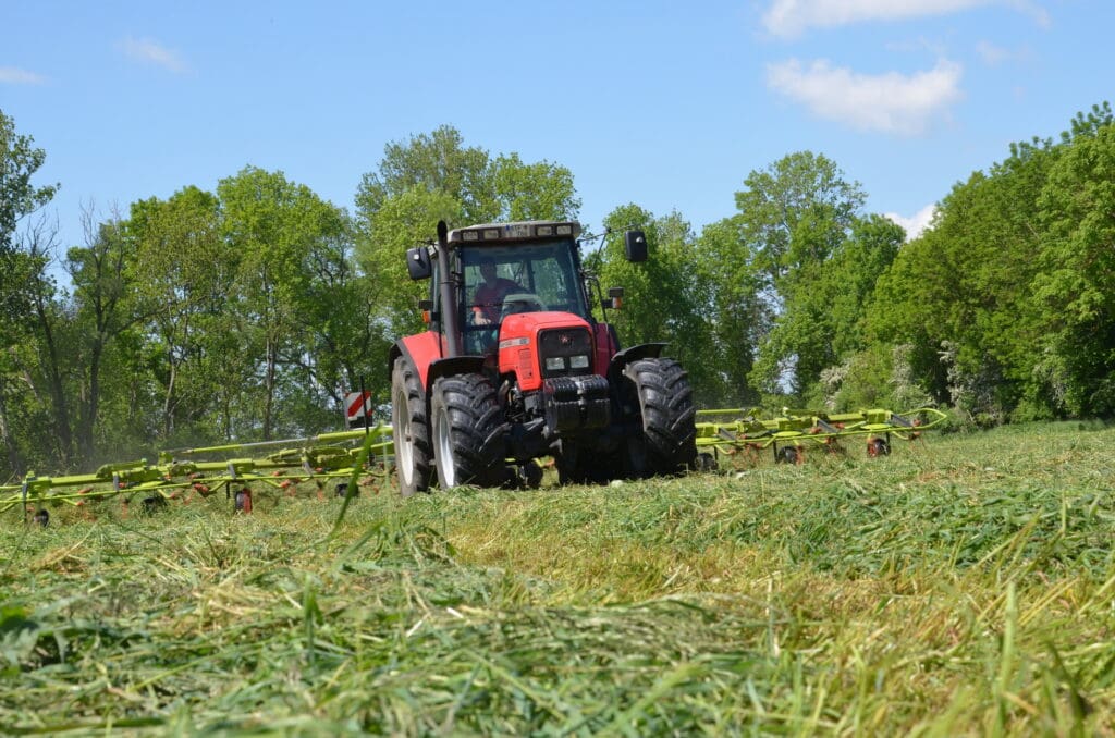 Mit dem Kreiselzettwender breitet Schlepperfahrer Dominik Hänsch das  Gras nach der Mahd zum Anwelken auf der Fläche aus.