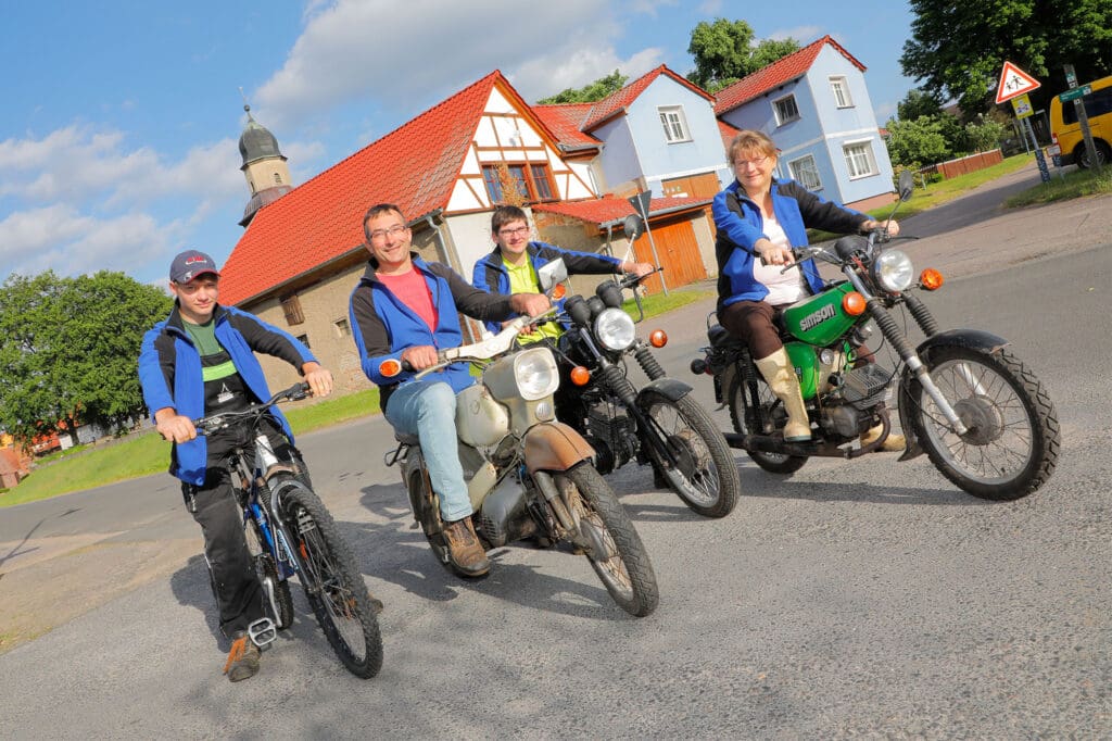 Familie Kienow vor dem Hof auf ihren Zweirädern. Wenn sie in Richtung Weide starten, setzen die Motorisierten noch Helme auf.