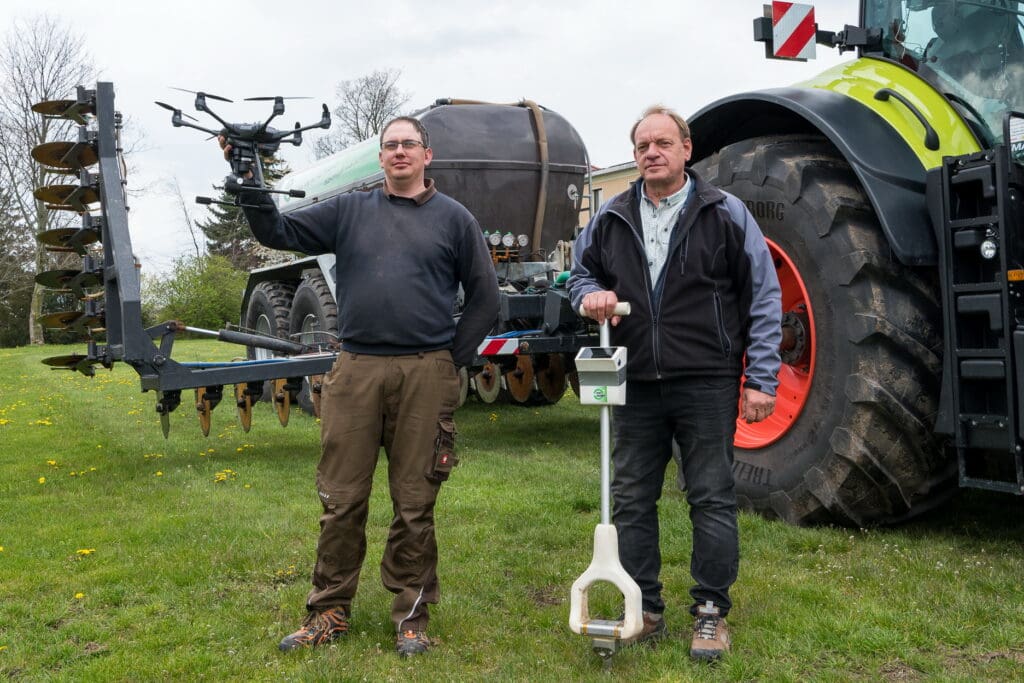 Firmenchef Uwe  Schiller mit dem  Sensorspaten zur  Bodenanalyse und  Martin Kretzschmar,  Leiter des Standorts  Dahme, mit einer  Drohne für die Kontrolle des Düngeerfolgs  vor dem selbst  entwickelten Scheibenrad-Injektionsgerät