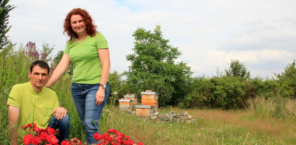 Das Imkerpaar Uwe und Katrin Bergmann vor den Bienenbeuten auf der großen Wiese.