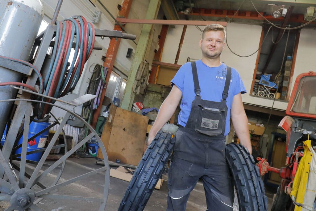 Landmaschinenschlosser André Mahnkopf mit Traktorreifen in seiner Werkstatt