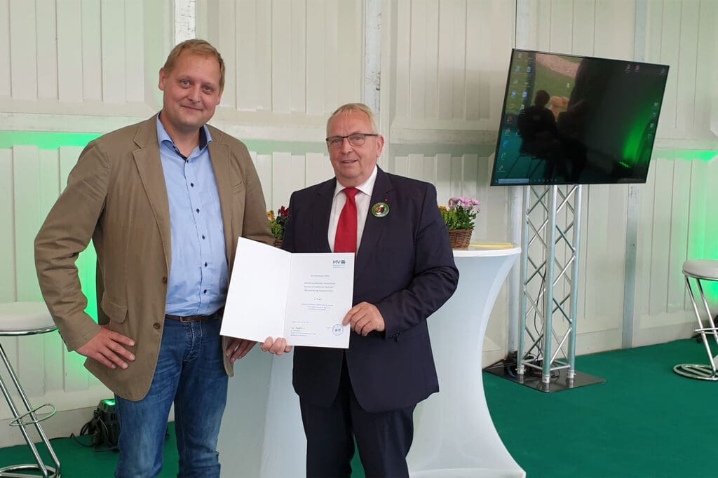 Michael Kühling wird von Till Backhaus auf der MeLa 2021 als "klimafreundlicher Landwirt" ausgezeichnet