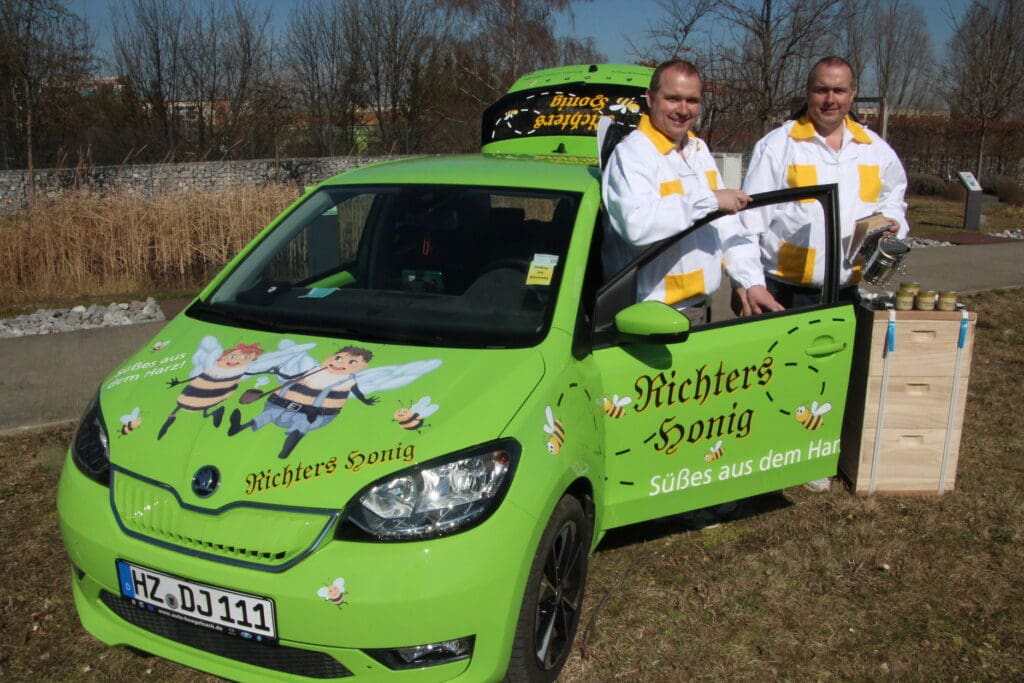 Wenn Dirk und Jörg Richter (v. l.) mit ihrem Bienen-Mobil unterwegs sind, „fahren“ Mutter Rositta und Uropa Willy auf der Motorhaube als fröhliche Bienen mit.