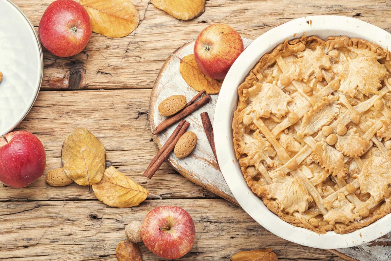 Traditional apple pie. Copyright: xMykolax Panthermedia27661915 Apfelkuchen steht auf einem Tisch mit Äpfeln, Zimtstangen und Blättern