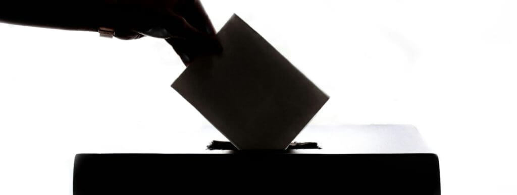 Stimmzettel in Wahl-Urne geben
