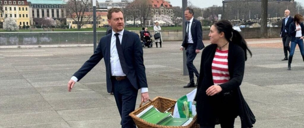 Ministerpräsident Kretschmer trägt die Unterschriften mit Tanja Turik, einer Mitinitiatorin der Resolution, in den Landtag.