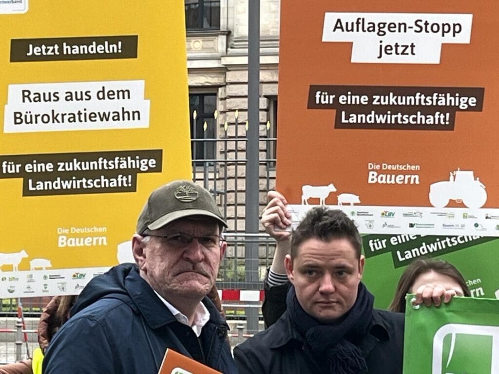 Henrik Wendorff, LBV-Präsident Brandenburg, und Benjamin Walker, Referent Agrarpolitik, politische Kommunikation beim Deutschen Bauernverband, sind bei den Protest-Aktionen in Berlin dabei. Im Hintergrund sind Demonstrationsplakate zu sehen.