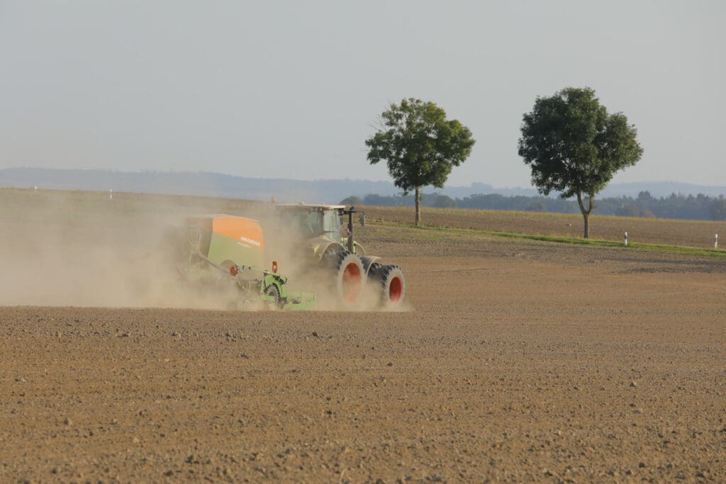 Klima Sachsen 2024: Ein Traktor fährt mit einer Drille über den Acker und säht aus.